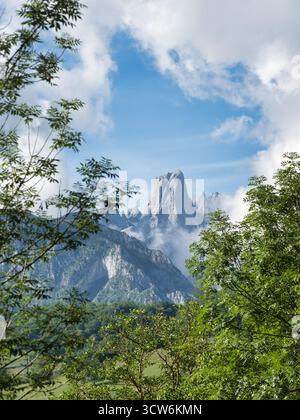 Majestätisches Naranjo de Bulnes Picos Europa - dramatische vertikale Aufnahme des Naranjo de Bulnes (PICU Urriellu) Gipfels, eingerahmt von Wolken und Wald, ein Symbol für Pi Stockfoto