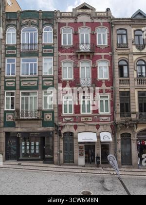 Farbenfrohe Fassaden und Geschäfte des historischen Gebäudes von Porto - Reihe traditioneller und farbenfroher historischer Gebäudefassaden mit Ziegelstein, Fliesen und Stein wi Stockfoto