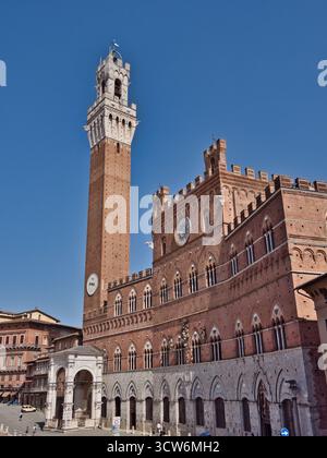 Torre del Mangia und Palazzo Pubblico auf der Piazza del Campo - breiter, flacher Blick auf den majestätischen, roten Backsteinpalast und den Uhrturm auf der geschäftigen Piazza Stockfoto