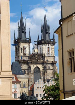 Kirchtürme hinter klassischem Gebäude - Nahaufnahme der dramatischen gotischen Türme der Kirche unserer Lieben Frau vor Týn im Kontrast zu einem Týn Stockfoto