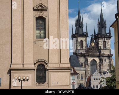 Kirchtürme hinter klassischem Gebäude - Nahaufnahme der dramatischen gotischen Türme der Kirche unserer Lieben Frau vor Týn im Kontrast zu einem Týn Stockfoto