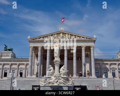 Pallas Athene Brunnen und Parlamentsgebäude - neoklassizistisches österreichisches Parlament mit dem majestätischen Pallas Athene Brunnen im Vordergrund auf einer sonne Stockfoto