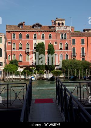 Venice Water Taxis vor Anker am Kanal - Ein symmetrischer Blick auf einen schmalen Holzsteg und zwei Wassertaxis (Motorboote), die in einem venezianischen cana vor Anker liegen Stockfoto