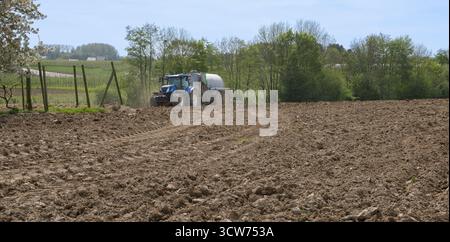 Ein Traktor auf einem Federfeld pflügt den Boden Stockfoto