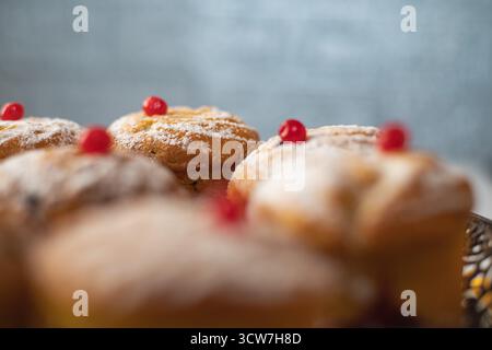 Frisch gebackene hausgemachte Muffins mit Puderzucker bestreut und mit roten Beeren auf einem Metallteller dekoriert, köstliches süßes Dessert zum Frühstück oder Stockfoto