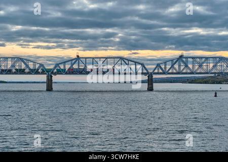 Samara, Russland - 28. September 2025: Industriegüterzug fährt bei Sonnenuntergang über die Syzran- oder Alexanderbrücke über die Wolga Stockfoto