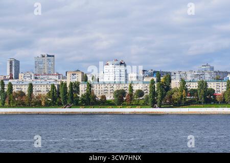Saratow, Russland - 29. September 2025: Malerischer Blick auf den Wolgadamm in Saratow mit Wohngebäuden und grünen Bäumen unter bewölktem Himmel Stockfoto