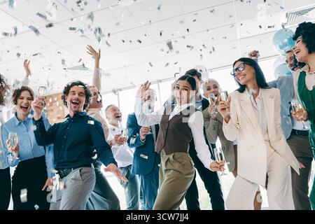 Verschiedene Kollegen genießen gemeinsam einen festlichen Moment an einem Arbeitsplatz im Unternehmen und betonen Einheit und Leistung mit einer fröhlichen Atmosphäre. Stockfoto