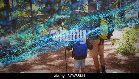 Zeigender Vater, der Sohn, der Wanderstock auf dem Pinienwald hält, Rucksäcke trägt, Kopierraum. Abenteuer, Entdeckungen, Reise, Natur, Wildnis Stockfoto