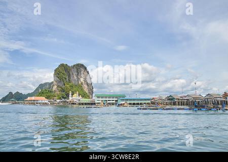 PHUKET, THAILAND - 12. NOVEMBER 2017: Malerisches Küstendorf mit felsigen Klippen und blauen Himmelsreflektionen auf ruhigem Wasser unter bewölktem Himmel. Stockfoto