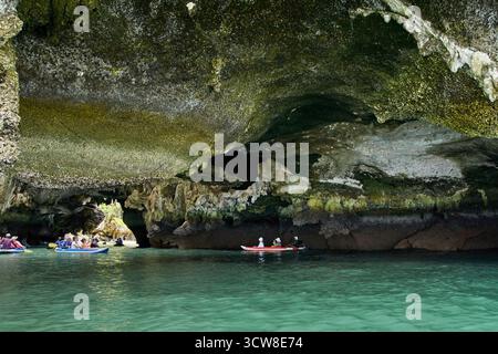 PHUKET, THAILAND - 12. NOVEMBER 2017: Gruppen erkunden die atemberaubende Küstenhöhle mit dem Kajak in klarem türkisfarbenem Wasser. Stockfoto