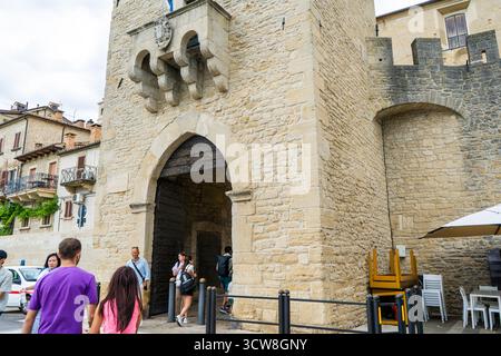 San Marino, San Marino - 13. Juli 2025: Alte Torarchitektur des Turms der Festung. Gebäudefassade Wandeingang. Sehenswürdigkeiten im Freien im Stadtzentrum. Burgdetail. Leute, die auf der Straße unterwegs sind Stockfoto