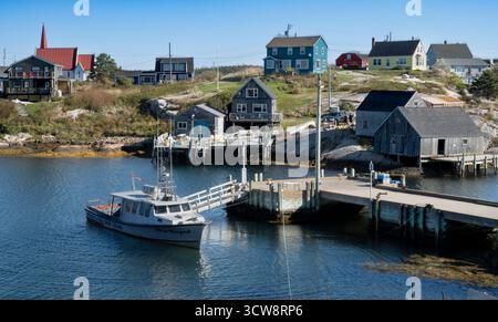 Peggy's Cove, NS - CA - 29. September 2025 farbenfrohe Häuser und Fischerhütten umgeben einen kleinen Hafen mit einem Ausflugsboot in Peggy's Cove, Nova Stockfoto