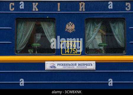 Otrakkala, Republik Karelien, Russland - 13. Mai 2024: Nahaufnahme der Seite eines blauen Zugwagens mit zwei Fenstern mit Vorhängen, Wagennummer Stockfoto