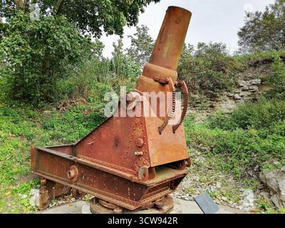 Eine alte, rostige Kanone mit einem großen Metallfass. Die Kanone steht auf dem Boden unter freiem Himmel. Stockfoto