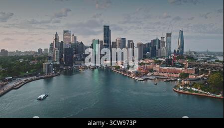 Australien, Sydney: Atemberaubender Blick auf die moderne Skyline von Sydney im ruhigen Hafenwasser. Berühmte Wolkenkratzer Stadtlandschaft beleuchtet durch sanftes Sonnenuntergangslicht. Panorama der Drohne Stockfoto