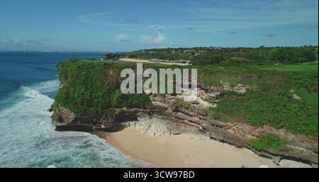 Atemberaubende Drohne, die die atemberaubende Schönheit des Pantai Dreamland Beach in Bali, Indonesien, mit stürzenden Wellen, dramatischen Klippen und üppiger Vegetation enthüllt Stockfoto