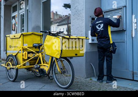 Mitarbeiter der Deutschen Post, die Post in Berlin zustellt. Die alltägliche Straßenszene spiegelt urbane Vielfalt und das tägliche Leben in einer modernen europäischen Stadt wider. Stockfoto
