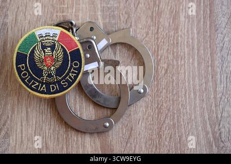 KIEW, UKRAINE - 6. SEPTEMBER 2025 Flicken der italienischen Staatspolizei und alte Handschellen aus Metall auf dem Tisch in Nahaufnahme Stockfoto