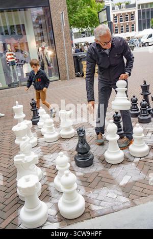 Großvater mit seinem kleinen Enkel spielt Freischach mit großen Schachfiguren Stockfoto