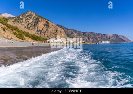 Kreta, Griechenland - 18. Oktober 2024: Blick auf die Küste von Agia Roumeli auf Kreta mit den Klippen der Samaria-Schlucht, die über dem Strand aufragen, und Fähren, die in der Nähe der ankerten Stockfoto