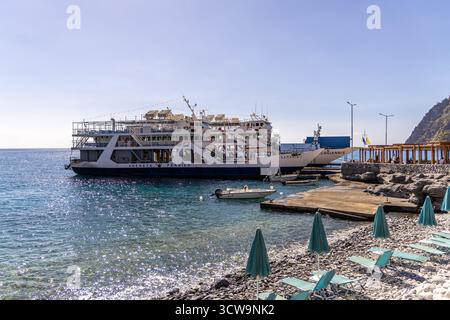 Kreta, Griechenland - 18. Oktober 2024: Küstenszene in Agia Roumeli, Kreta Fährschiff an Rocky Shoreline und Waterfront Path. Stockfoto