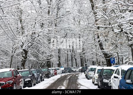Geparkte Autos am Straßenrand an einem verschneiten Wintertag. Straße mit Schnee bedeckt Stockfoto