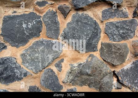 Graue Steinwand mit sandfarbenem, strukturiertem abstraktem Hintergrund aus Mörtel Stockfoto