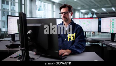 Ein erfahrener FBI-Agent untersucht mehrere Monitore in der Büroumgebung. Stockfoto