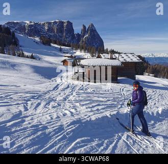 Skifahrer auf der Seiser Alm (Seiser Alm), St. Ulrich, Gröden, Südtirol, italienische Dolomiten – mit Blick auf Berghütten und Schlern im Hintergrund. Stockfoto