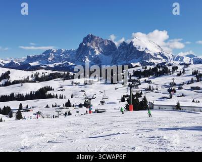 Schneebedeckte Skipisten auf der Seiser Alm in Südtirol, mit dem berühmten Langkofel-Gipfel, der sich hinter den Dolomiten erhebt Stockfoto