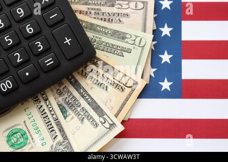 US-Dollar-Geldscheine und Taschenrechner auf amerikanischer Flagge Nahaufnahme. Geldinvestitionskonzept und Steuerzahlung Stockfoto
