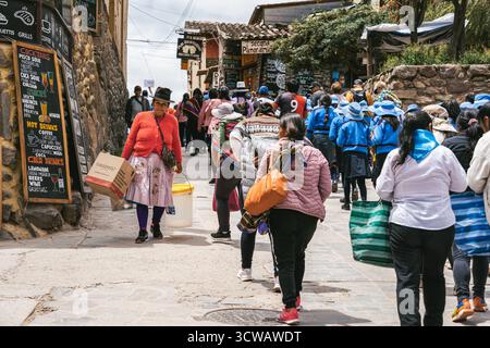 Ollantaytambo, Peru - 17. März 2025: Hochrangige peruanische Frau, die auf einer überfüllten Straße in Ollantaytambo spaziert. Stockfoto
