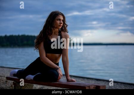 Genießen Sie die ruhige Praxis des Yoga am ruhigen See, während die wunderschöne Dämmerung einsetzt Stockfoto