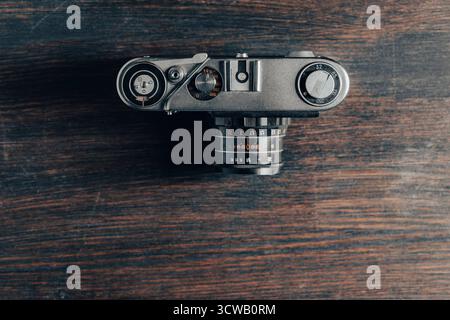 Alte Retro-Fotokamera auf hölzernem Hintergrund, Draufsicht, Kopierraum, Nahaufnahme. Veralteter Nostalgie-Stil Stockfoto