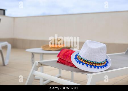 Sonnenliegen mit Hüten und Handtüchern auf der Dachterrasse aus der Nähe Stockfoto