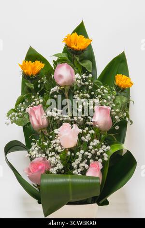 Blumenanordnung aus rosa Rosen, gelben Sonnenblumen und weißem Babyatem auf weißem Hintergrund. Stockfoto