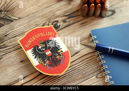 KIEW, UKRAINE - 6. SEPTEMBER 2025 Österreich Bundespolizeiflicken mit Kugeln und Notizblock auf Holztisch Nahaufnahme Stockfoto