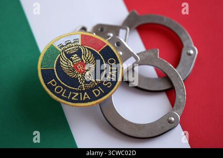 KIEW, UKRAINE - 6. SEPTEMBER 2025 Flicken und Handschellen der italienischen Staatspolizei auf Nationalflagge Nahaufnahme Stockfoto