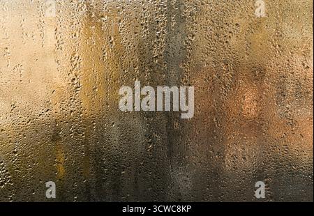Nasses Glas. Winzige Feuchteperlen schmücken das beschlagene Fenster, den Hintergrund. Einige Tropfen rutschen langsam nach unten und hinterlassen flüchtige Spuren auf Glas. Abstrakte Ba Stockfoto
