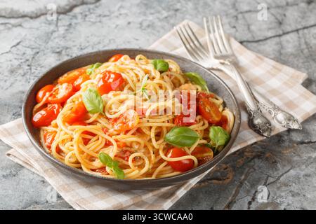 Italienische Spaghetti Margherita mit Tomaten, Mozzarella, Basilikum, Knoblauch und Olivenöl in Nahaufnahme auf einem Teller auf dem Tisch. Horizontal Stockfoto
