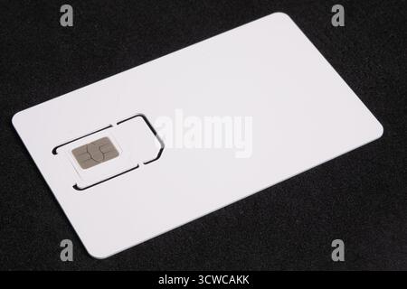 Weiße SIM-Karte auf schwarzem Hintergrund isoliert. SIM-Karte für Mobiltelefon, Nahaufnahme, Draufsicht Stockfoto