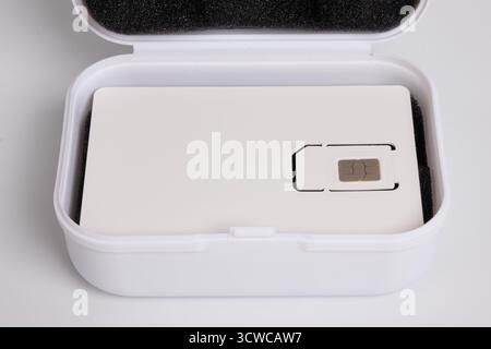 Nahaufnahme einer neuen Handy-SIM-Karte in der weißen Trägerverpackung über einer offenen Aufbewahrungsbox Stockfoto
