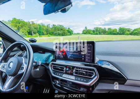 Nahaufnahme des Innenraums des elektrischen BMW iX3 M mit Armaturenbrett und Infotainment-Display vor grünem Hintergrund. Stockfoto