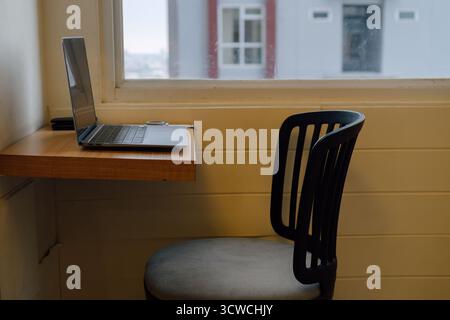 Minimalistischer Arbeitsbereich Mit Laptop Und Stuhl Am Fenster Mit Natürlichem Licht Stockfoto