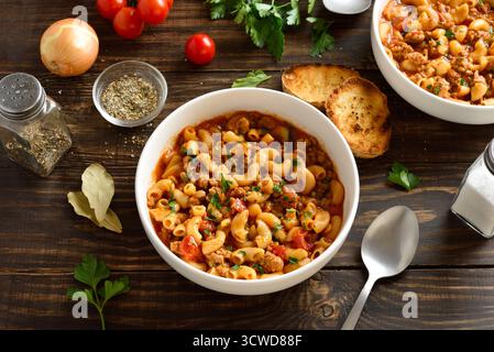 Amerikanisches Gulasch, Gericht mit gemahlenem Rindfleisch und Ellenbogenmakkaroni in Tomatensauce in einer Schüssel auf Holztisch. Nahansicht Stockfoto