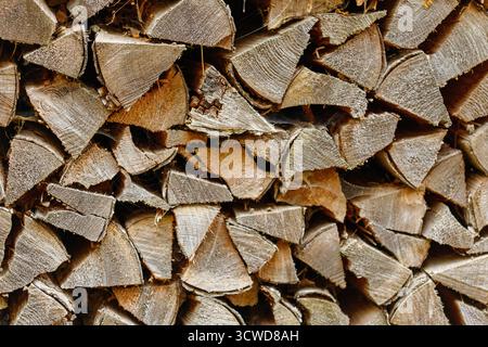 Ein dichter Blick von oben auf einen Haufen gehackten Holzes mit rauen, strukturierten Oberflächen in Braun- und Grautönen, sichtbarer Körnung und einigen Spinnennetzen Stockfoto