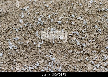 Eine Nahaufnahme von oben nach unten auf loses Aggregatmaterial, bestehend aus kleinen braunen Kieselsteinen und weißem Kies. Stockfoto