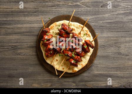 Tandoori Hähnchenspieße werden in Gewürzen, Joghurt und Zitronensaft auf Servierplatte auf hölzernem Hintergrund mariniert. Draufsicht, flach Stockfoto