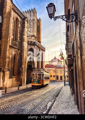 Eine gelbe Straßenbahn fährt an der gotischen Sé-Kathedrale in Lissabon vorbei Stockfoto